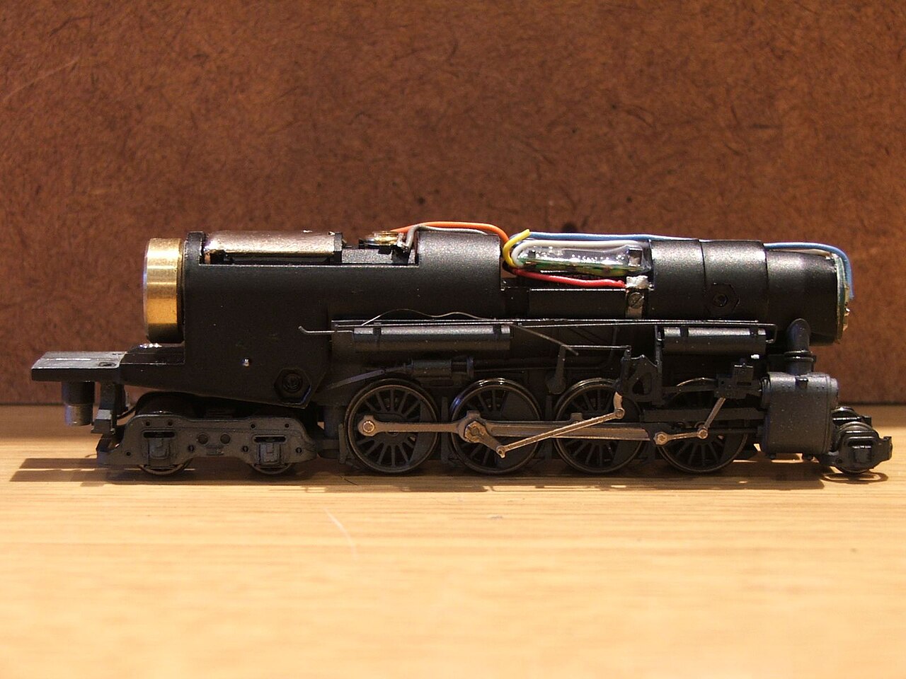 An N scale steam locomotive chassis with its shell removed and a small circuit board wired in on top
