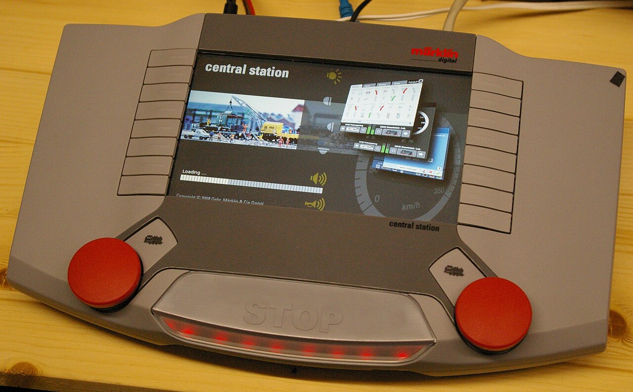 A Märklin Central Station 2 digital controller with a screen in the middle and a red speed knob at each lower corner