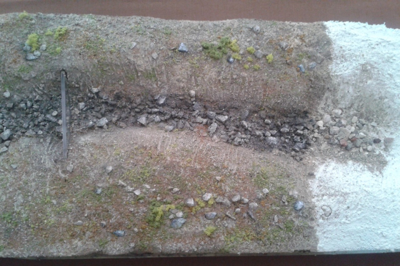 A foam block with its ground already painted earth colours, with crushed stone and a little ground cover, and white plaster still showing on the right