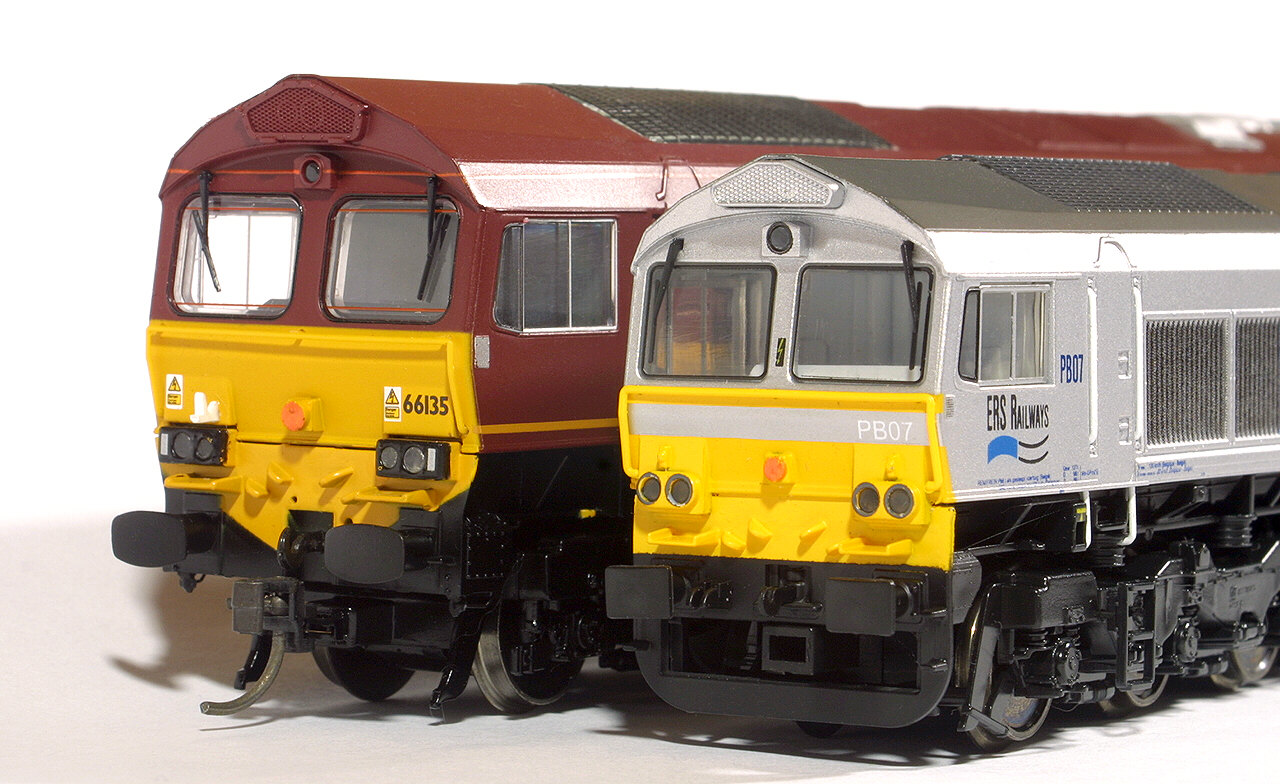 Two models of the same British Class 66 diesel locomotive side by side; the OO model on the left is visibly larger than the HO model on the right