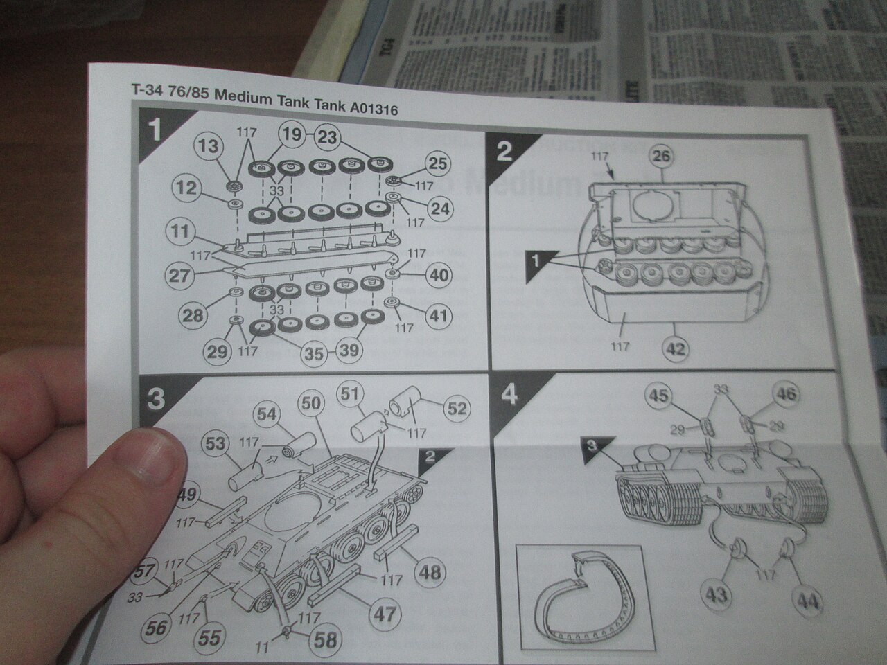 A hand holding the first page of an Airfix T-34 instruction sheet, showing four numbered assembly steps